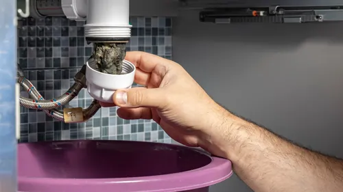 A person inspecting damaged pipe