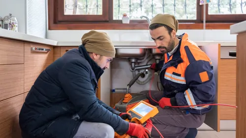 Two people inspecting clog in sink